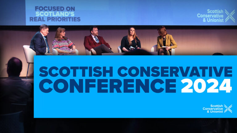 Photograph of a panel on stage with a text box containing the title, 'Scottish Conservative Conference 2024'